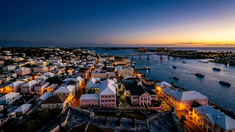 Nassau's pastel colonial rooftops and harbour seen from a hilltop at dusk.